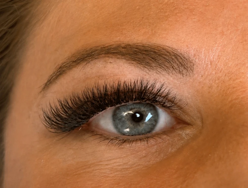Nahaufnahme einer Wimpernverlängerung an einem blauen Auge